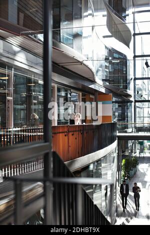 Business professionals discussing in atrium at modern office Stock Photo