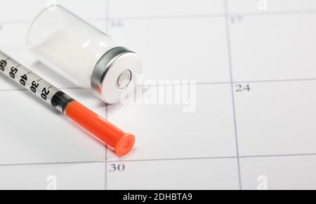 syringe with orange cannula and transparent vaccine vial with aluminum closure, PCR vial with cap, calendar envelope Stock Photo