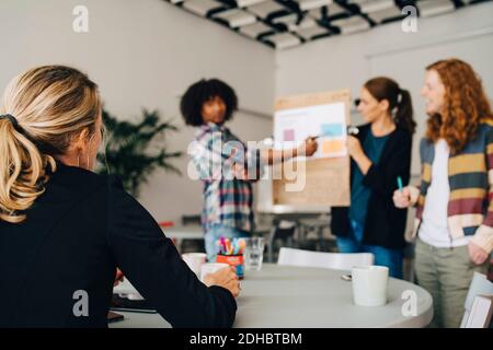 Female manager looking at confident technicians explaining strategy on placard in creative office Stock Photo