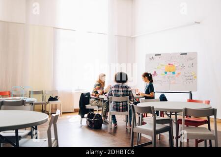 Team of multi-ethnic engineers working at table by whiteboard in creative office Stock Photo