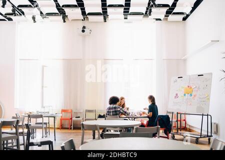 Multi-ethnic team of technicians working at table by whiteboard in creative office Stock Photo