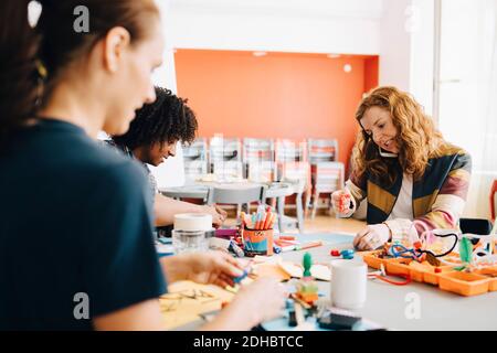 Businesswoman talking on mobile phone while sitting at table with colleagues working in creative office Stock Photo