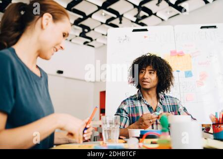 Multi-ethnic business colleagues discussing while working at table in creative office Stock Photo