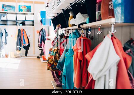 Various clothes hanging from hooks in cloakroom at preschool Stock Photo