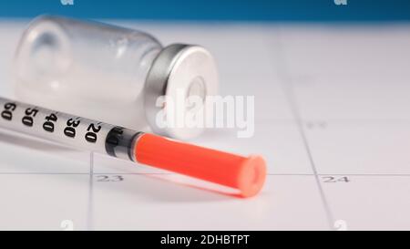 syringe with orange cannula and transparent vaccine vial with aluminum closure, PCR vial with cap, calendar envelope Stock Photo