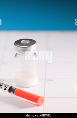 syringe with orange cannula and transparent vaccine vial with aluminum closure, PCR vial with cap, calendar envelope Stock Photo