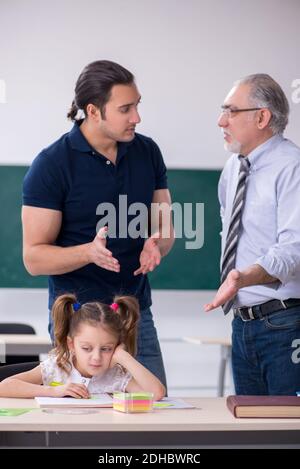 Young parent, old male teacher and little girl in the classroom Stock Photo