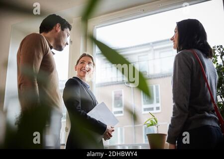 Smiling female agent discussing with customers at new apartment Stock Photo