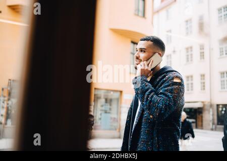 Young businessman talking on smart phone seen through window Stock Photo
