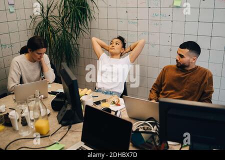 High angle view of multi-ethnic colleagues relaxing at desk in creative office Stock Photo