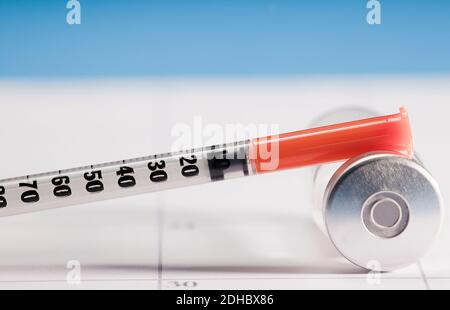 syringe with orange cannula and transparent vaccine vial with aluminum closure, PCR vial with cap, calendar envelope Stock Photo