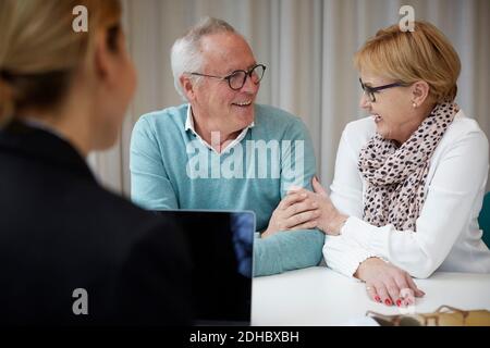Smiling retired couple with female agent in real estate office Stock Photo