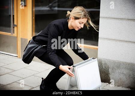 Real estate agent arranging blank signboard on sidewalk in city Stock Photo