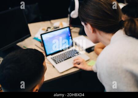 High angle view of businesswoman using laptop amidst colleagues at creative office Stock Photo