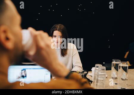 Male programmer drinking coffee while confident young female hacker working at desk in small office Stock Photo