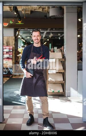 Portrait of smiling mature entrepreneur standing in store Stock Photo