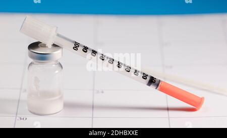 syringe with orange cannula and transparent vaccine vial with aluminum closure, PCR vial with cap, calendar envelope Stock Photo