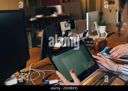 Cropped image of mature computer programmer using laptop and smart phone in office Stock Photo
