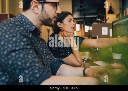 Female computer programmer with colleague discussing over coding in office Stock Photo