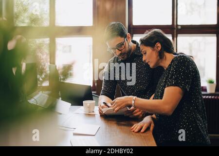 Multi-ethnic business people discussing over documents at desk in office Stock Photo