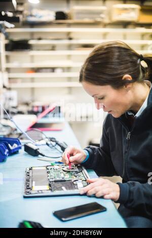 Female engineer repairing computer equipment in workshop Stock Photo