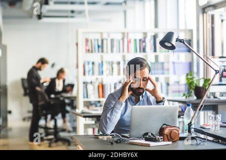 Frustrated businessman looking at laptop while sitting in office Stock Photo
