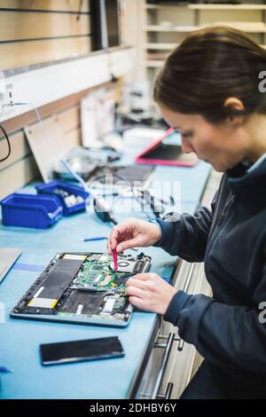 Mature female engineer repairing equipment in computer store Stock Photo