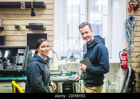 Portrait of confident smiling computer engineers working in electronics store Stock Photo