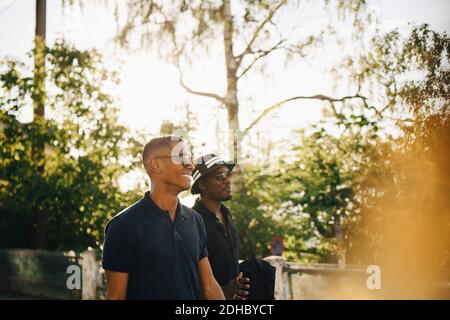 Male friends talking while walking in forest Stock Photo