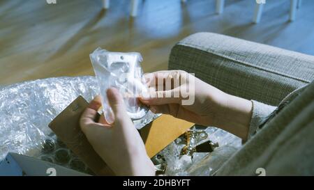 woman unboxing in living room small cardboard box containing metallic vintage number three for house after online shopping Stock Photo