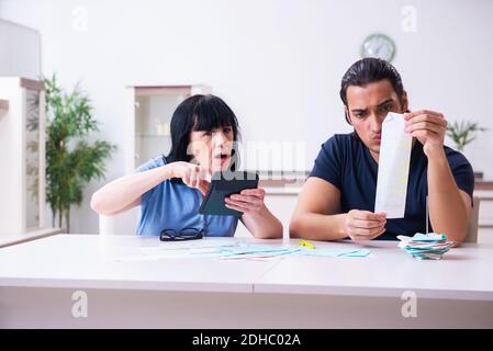 Female pensioner and her young son in budget planning concept Stock Photo