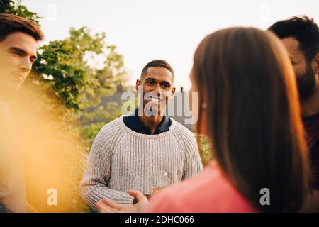 Multi-ethnic friends talking while standing in yard during social gathering Stock Photo