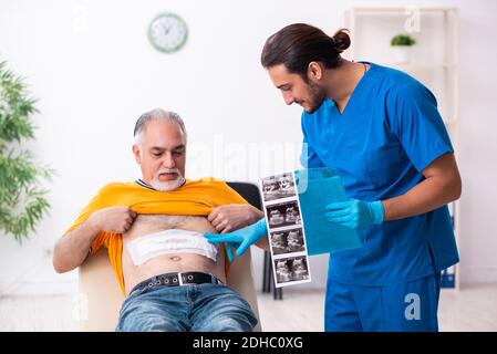 Old man visiting young male doctor Stock Photo