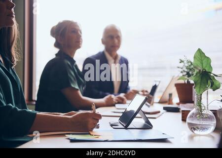 Business colleagues sitting at conference table in board room during meeting Stock Photo