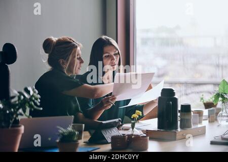 Confident female entrepreneurs discussing over documents during meeting in board room at office Stock Photo