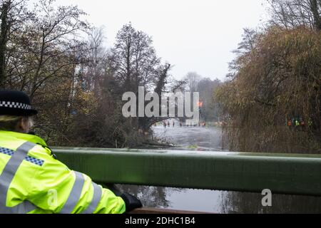 Denham, UK. 8th December, 2020. A police officer observes a large security operation to extract Dan Hooper, widely known as Swampy during the 1990s, from a bamboo tripod positioned in the river Colne in order to delay the building of a bridge as part of works for the controversial HS2 high-speed rail link. Credit: Mark Kerrison/Alamy Live News Stock Photo