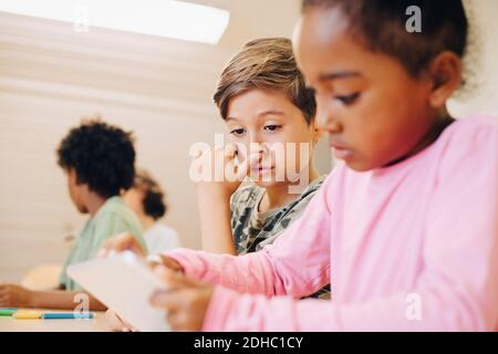 Boys using digital tablet while learning at classroom Stock Photo