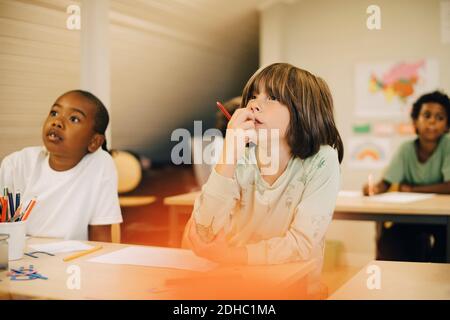 Male students concentrating at desk in classroom Stock Photo