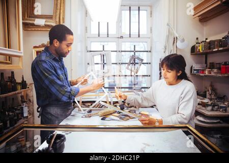 Male and female artists making picture frame at workbench in store Stock Photo