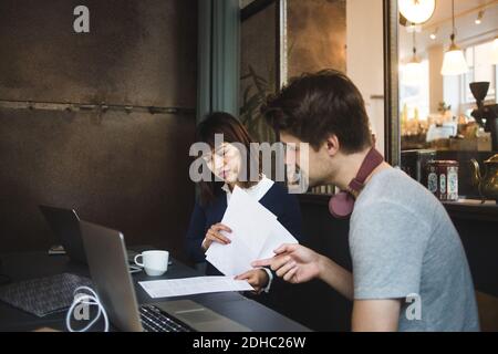 Confident creative colleagues discussing over documents at desk in office Stock Photo