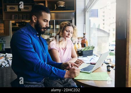 Colleagues with laptop and documents working at table in deli Stock Photo