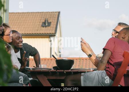 Senior man photographing family sitting at table on porch Stock Photo