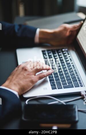 Hands of businessman typing on laptop keyboard at desk in creative office Stock Photo