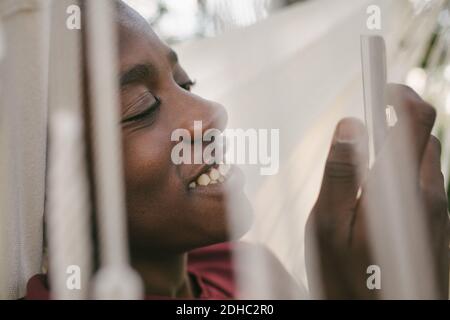 Smiling boy using mobile phone while relaxing on hammock Stock Photo
