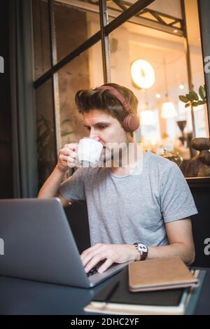 Confident businessman drinking coffee while using laptop at desk in office Stock Photo