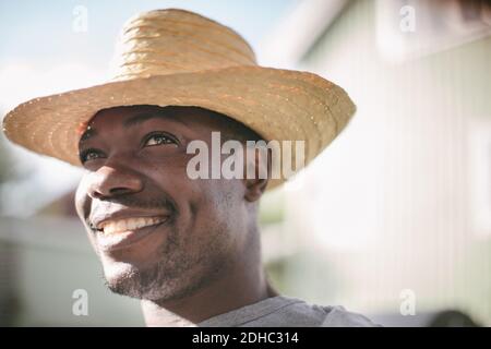 Smiling mid adult man looking away while wearing straw hat during garden party Stock Photo