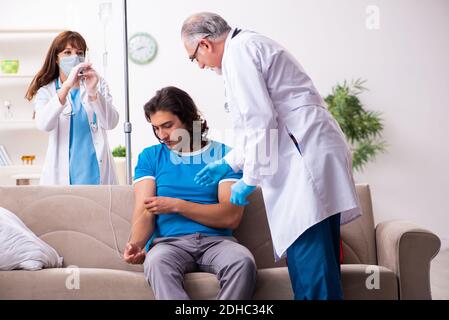 Two doctors visiting sick young man at home Stock Photo