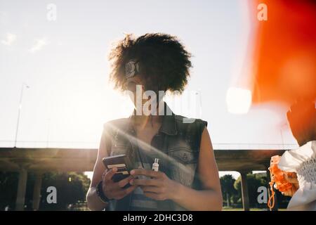 Young man with electronic cigarette using mobile phone in summer Stock Photo