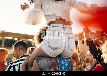 Man carrying friend on shoulder while enjoying at music festival Stock Photo
