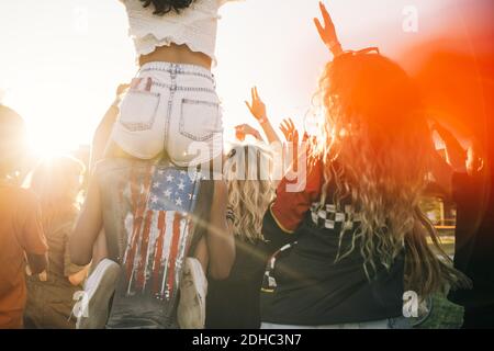 Man carrying friend on shoulder while enjoying in crowd at music event Stock Photo